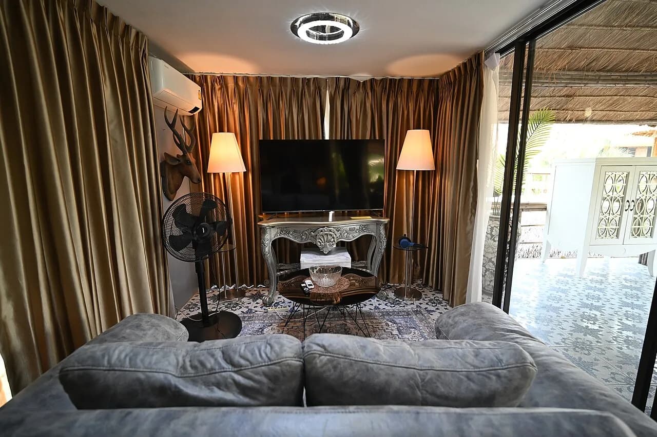A living room with a grey sofa facing a large flat-screen TV on a console