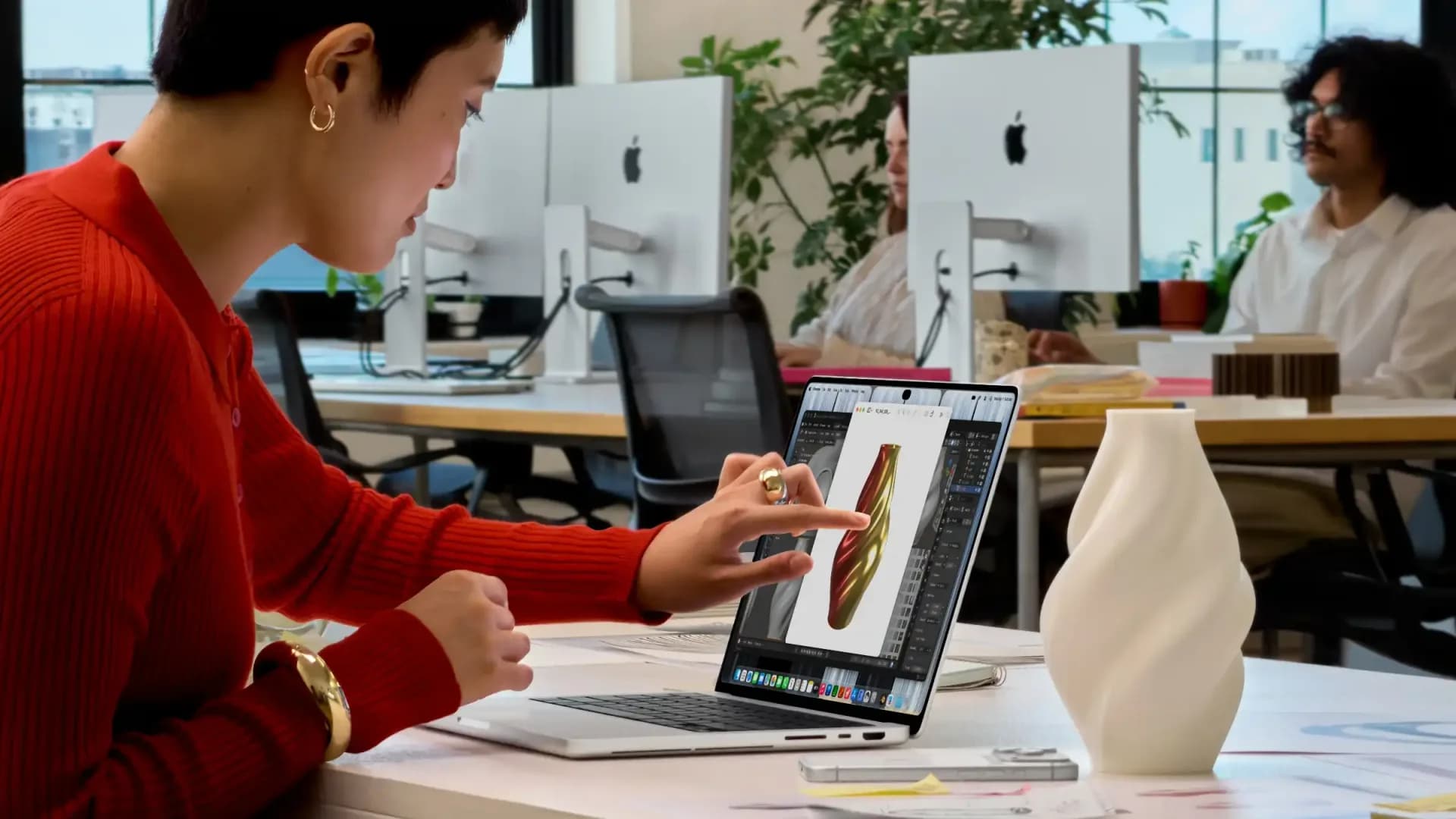 A MacBook Pro laptop shown with a finger touching its screen display