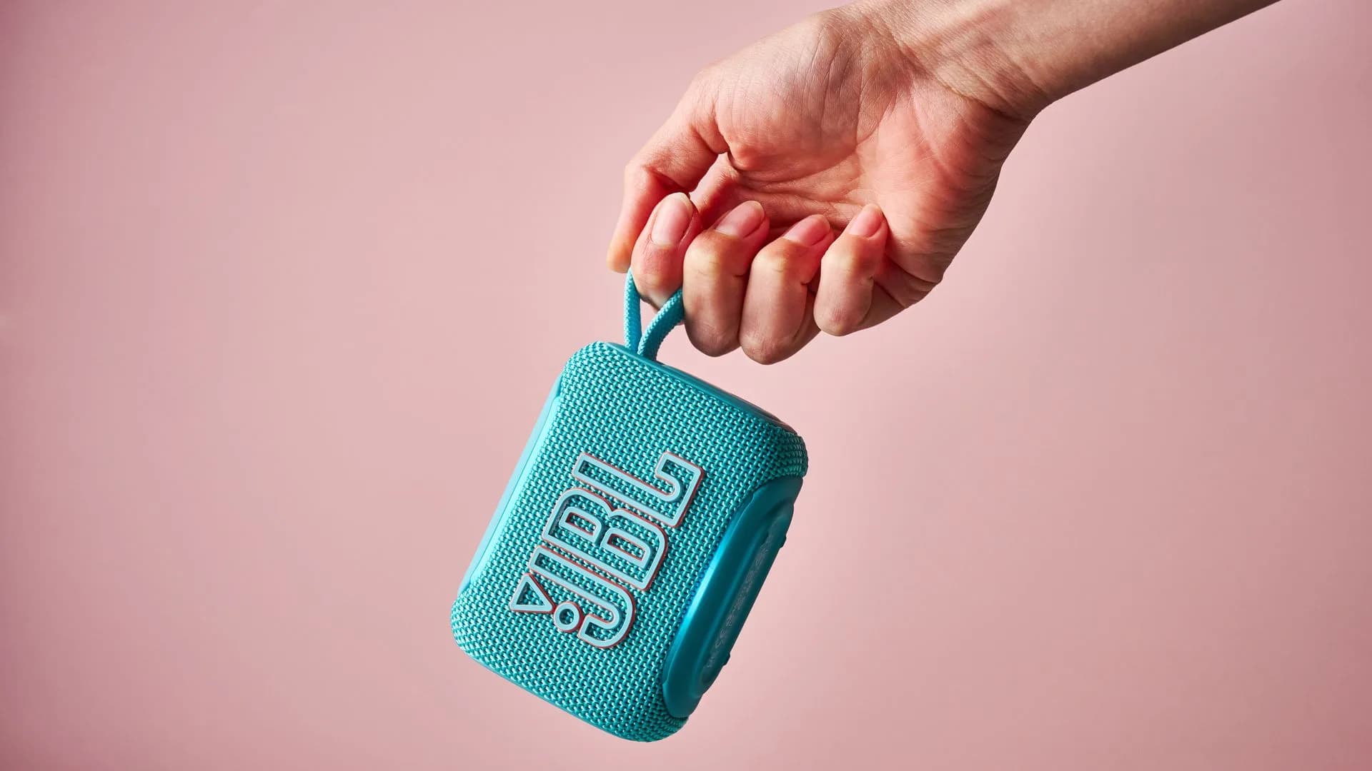 JBL Go 5 Bluetooth speaker in matte black, sitting on a tiled bathroom shelf beside a toothbrush holder