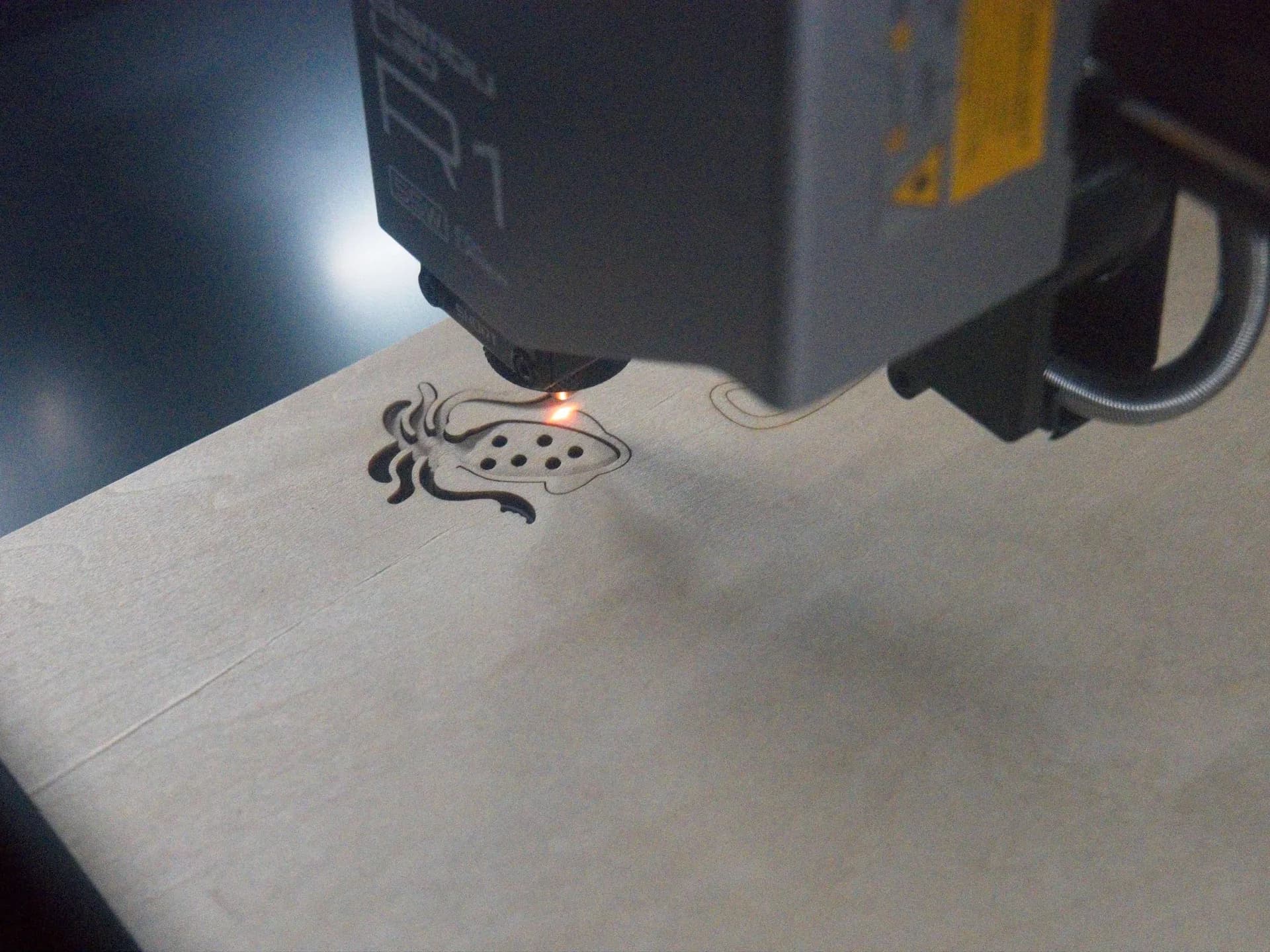 The Bambu Lab R1 laser cutter sitting on a workbench with its internal lid visible