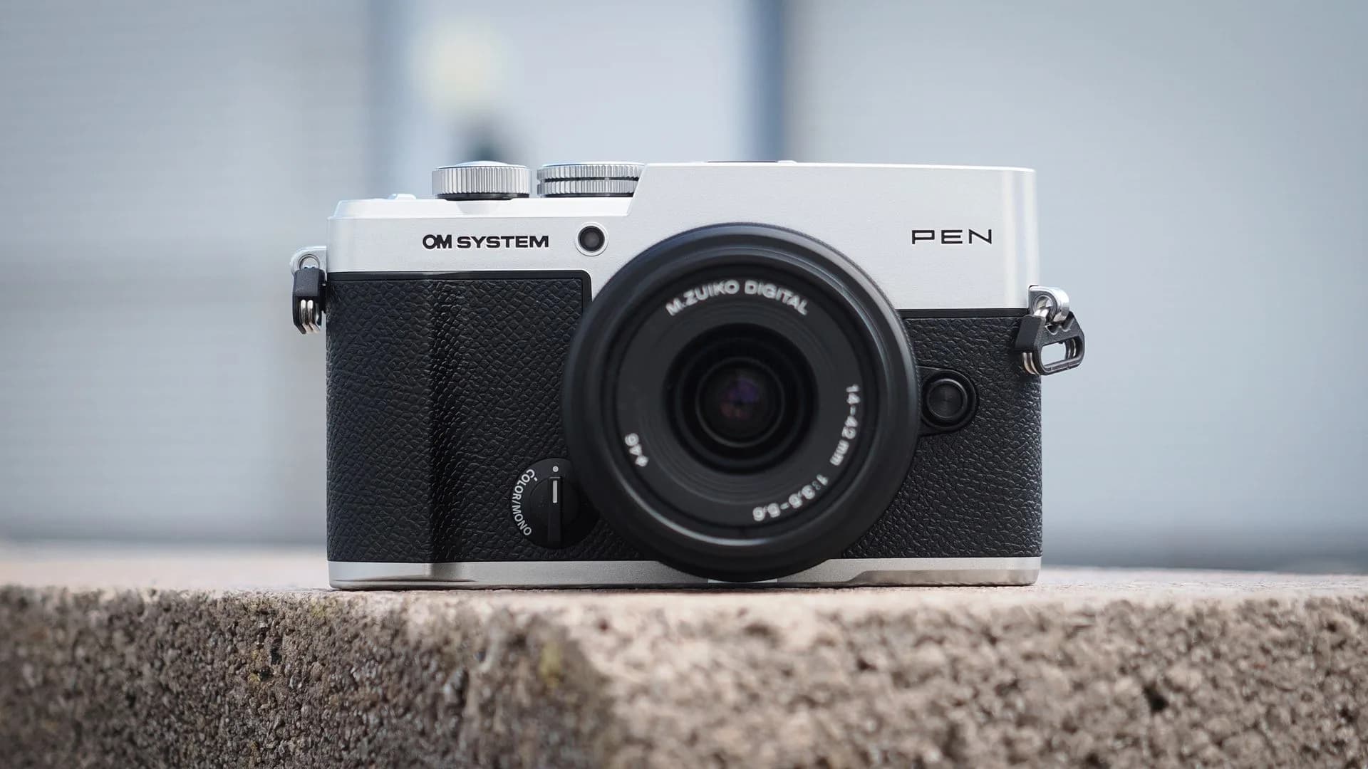 Front angle of the OM System PEN mirrorless camera showing its compact body and lens mount.