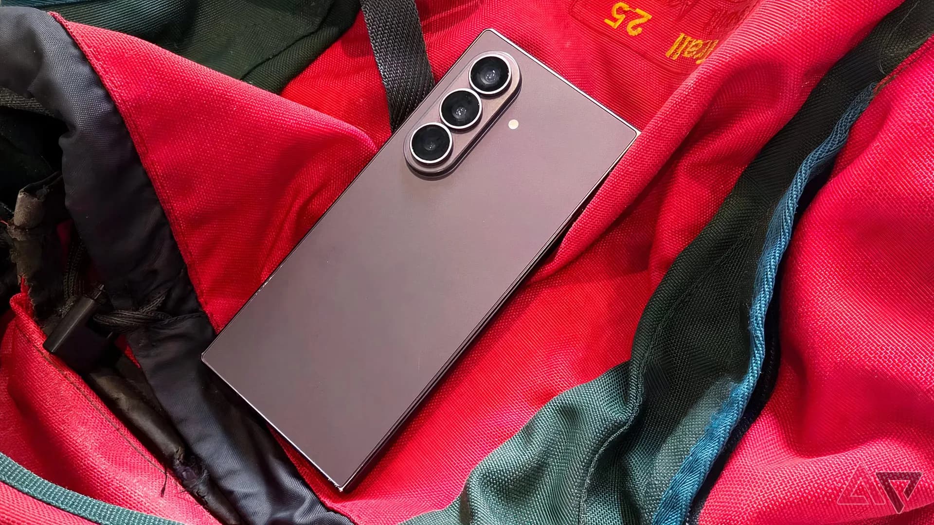 Samsung Galaxy Z Fold 8 Ultra shown unfolded with its inner display open, next to travel items like a boarding pass and headphones.