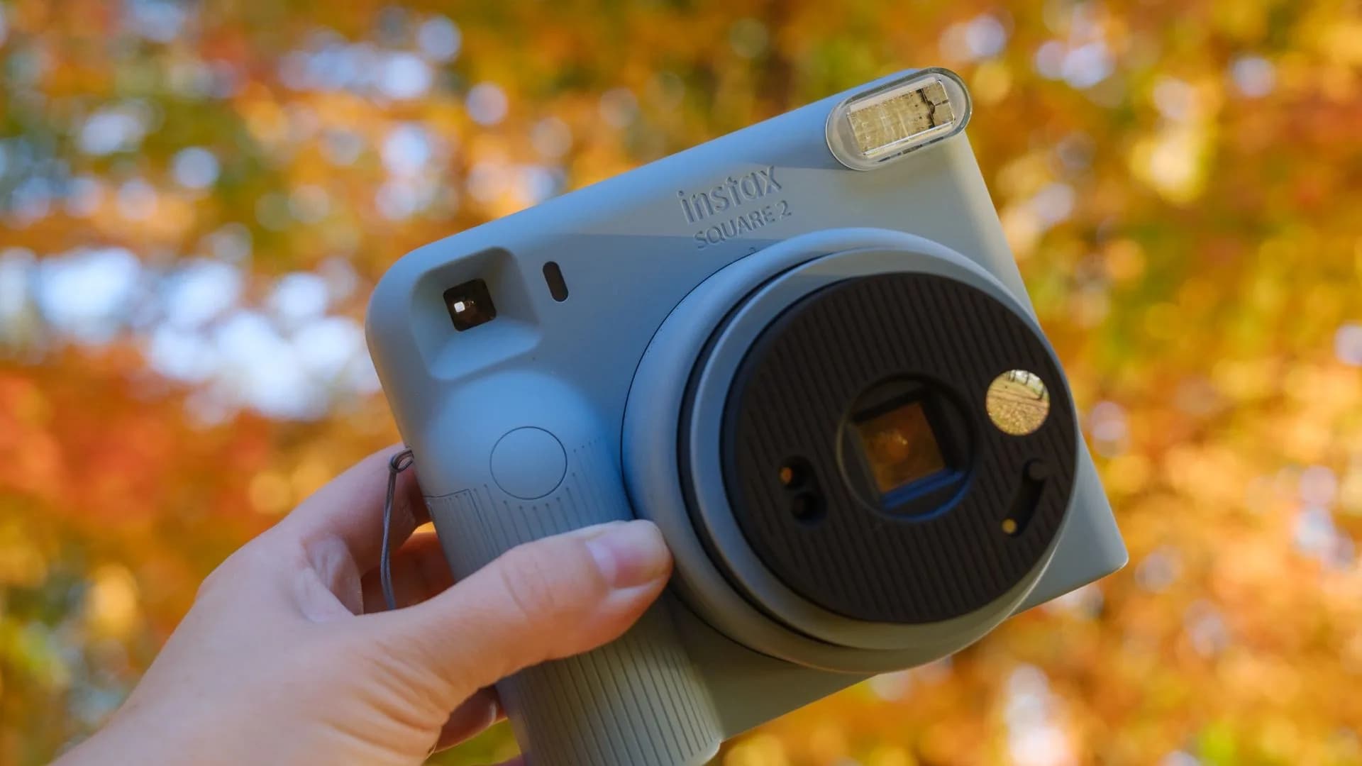 Front view of the Fujifilm Instax Square 2 instant film camera showing the lens dial and filter toggle.
