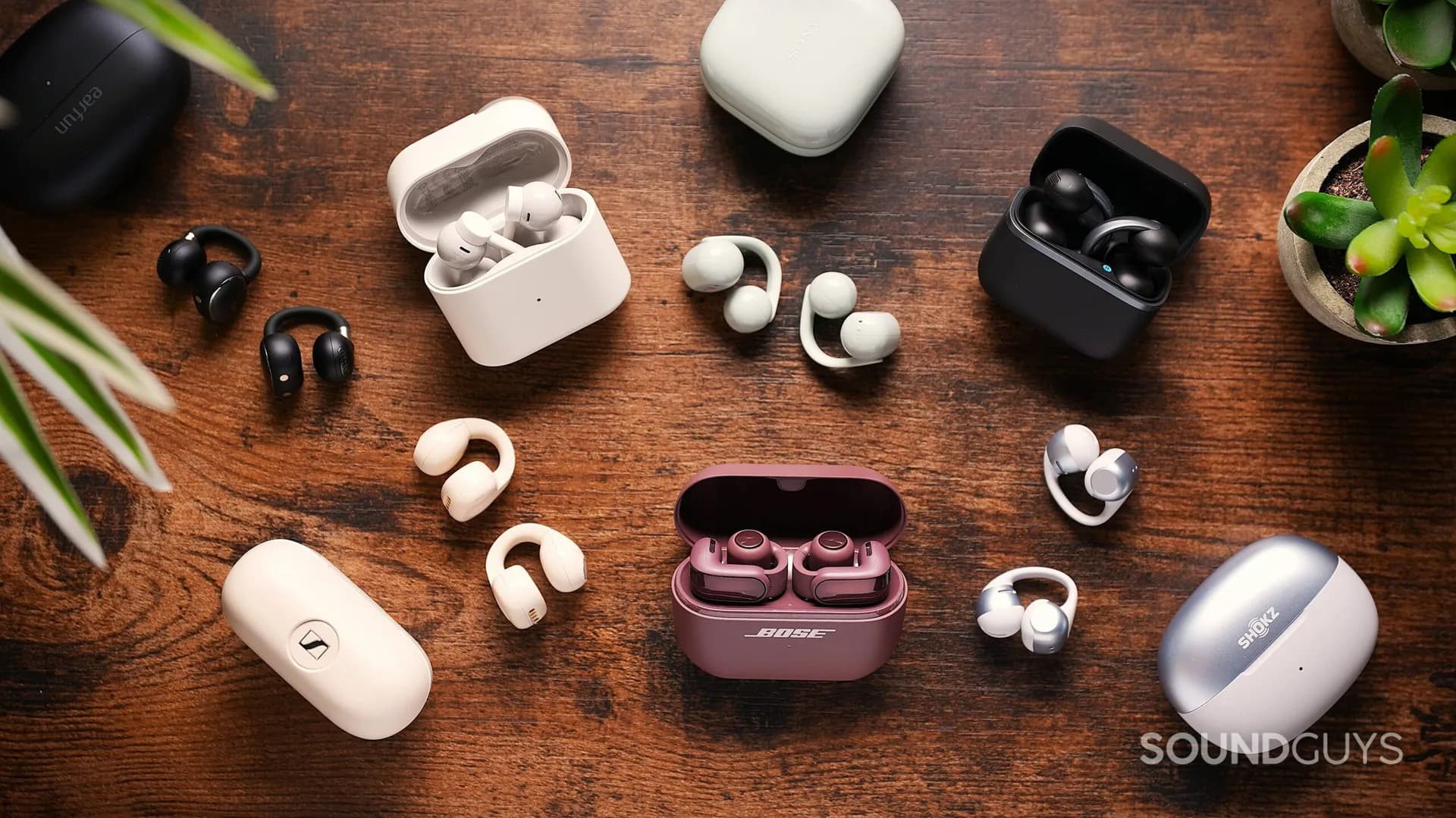 A pair of clip-on open earbuds sitting next to a charging case on a flat surface