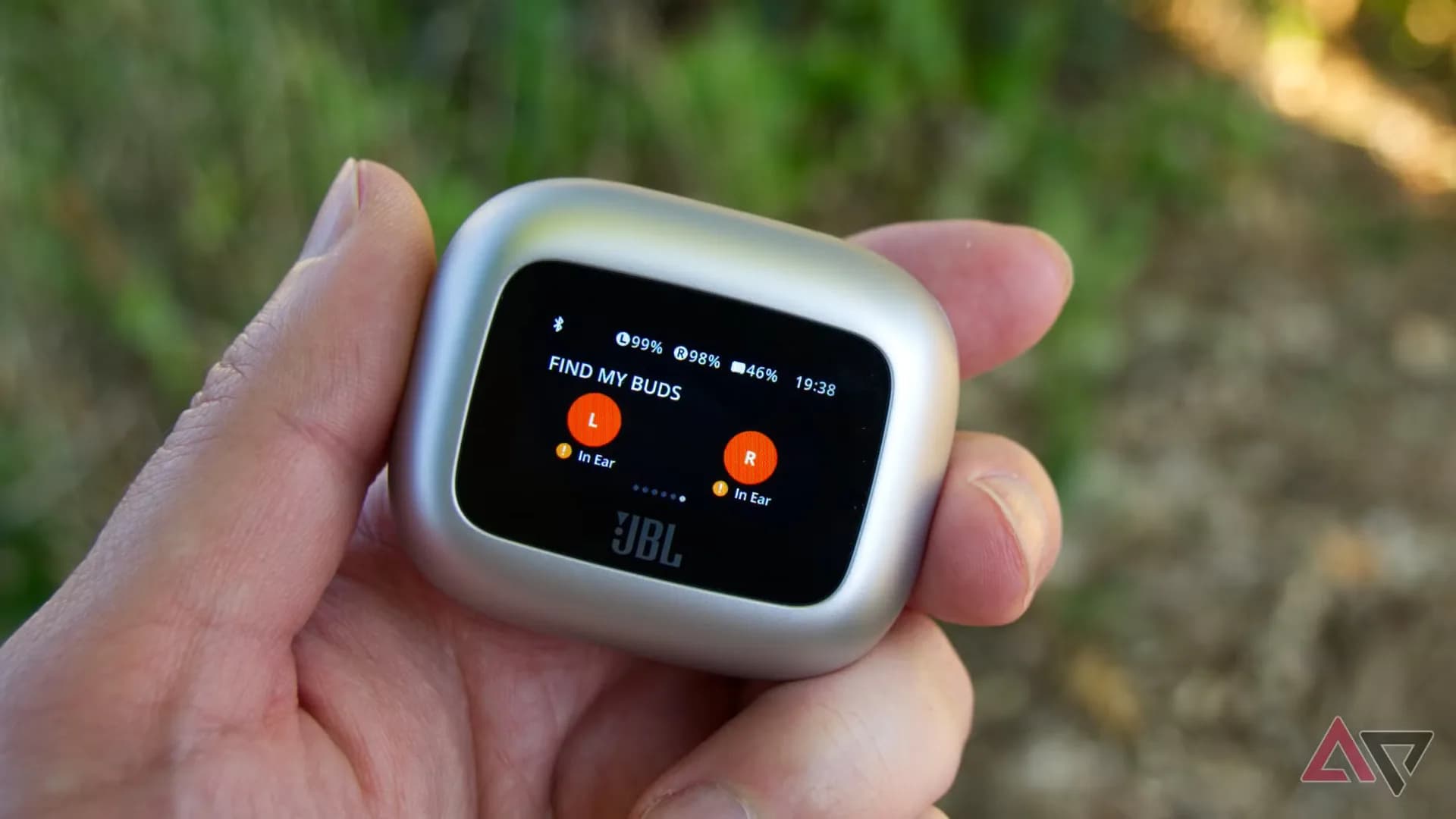 JBL Live Buds 3 wireless earbuds next to their charging case with a built-in screen