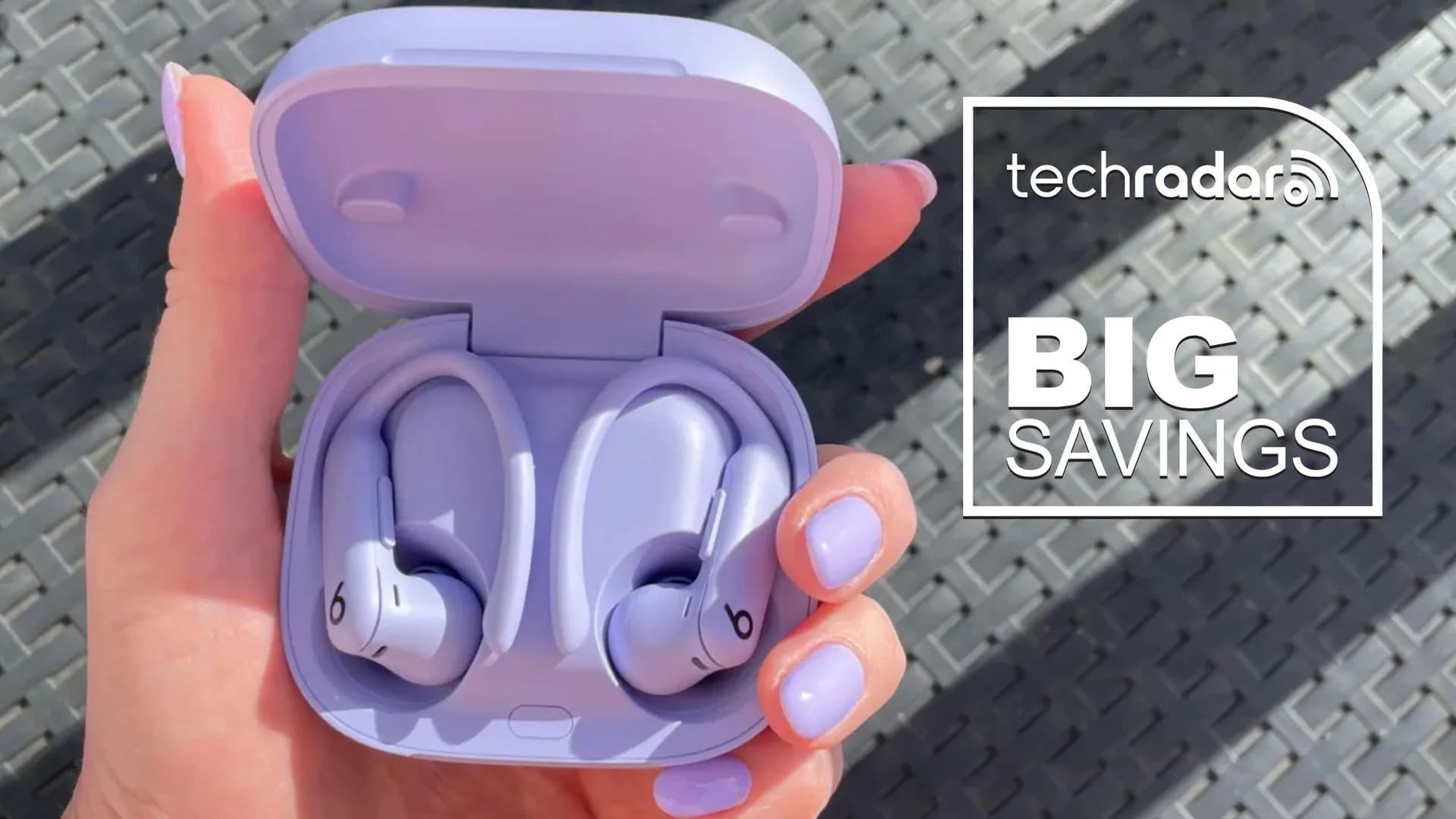 Beats Powerbeats Pro 2 earbuds in Hyper Purple, resting on a gym towel beside running shoes.