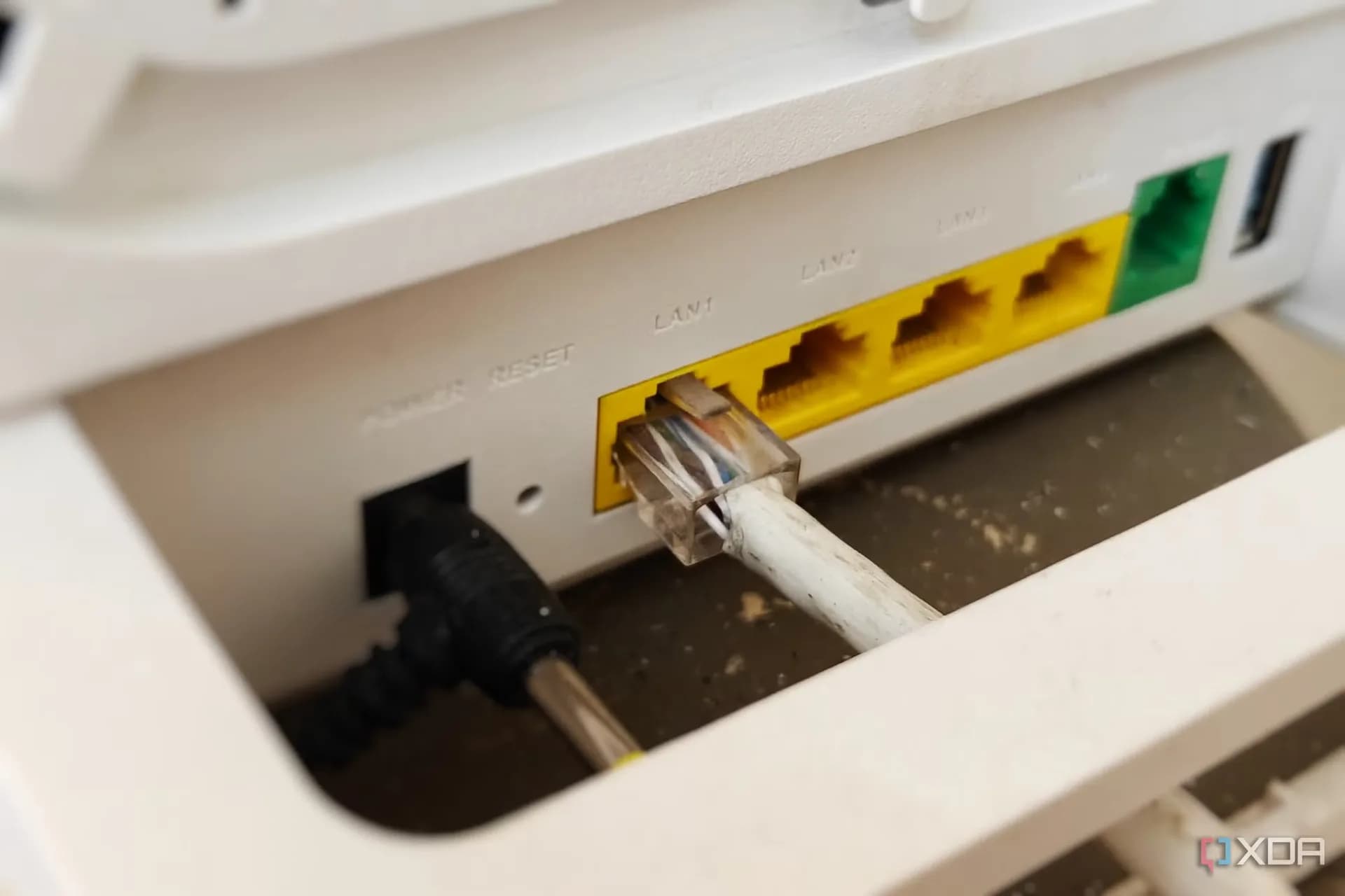 A white Wi-Fi router sitting on a wooden desk next to an Ethernet cable