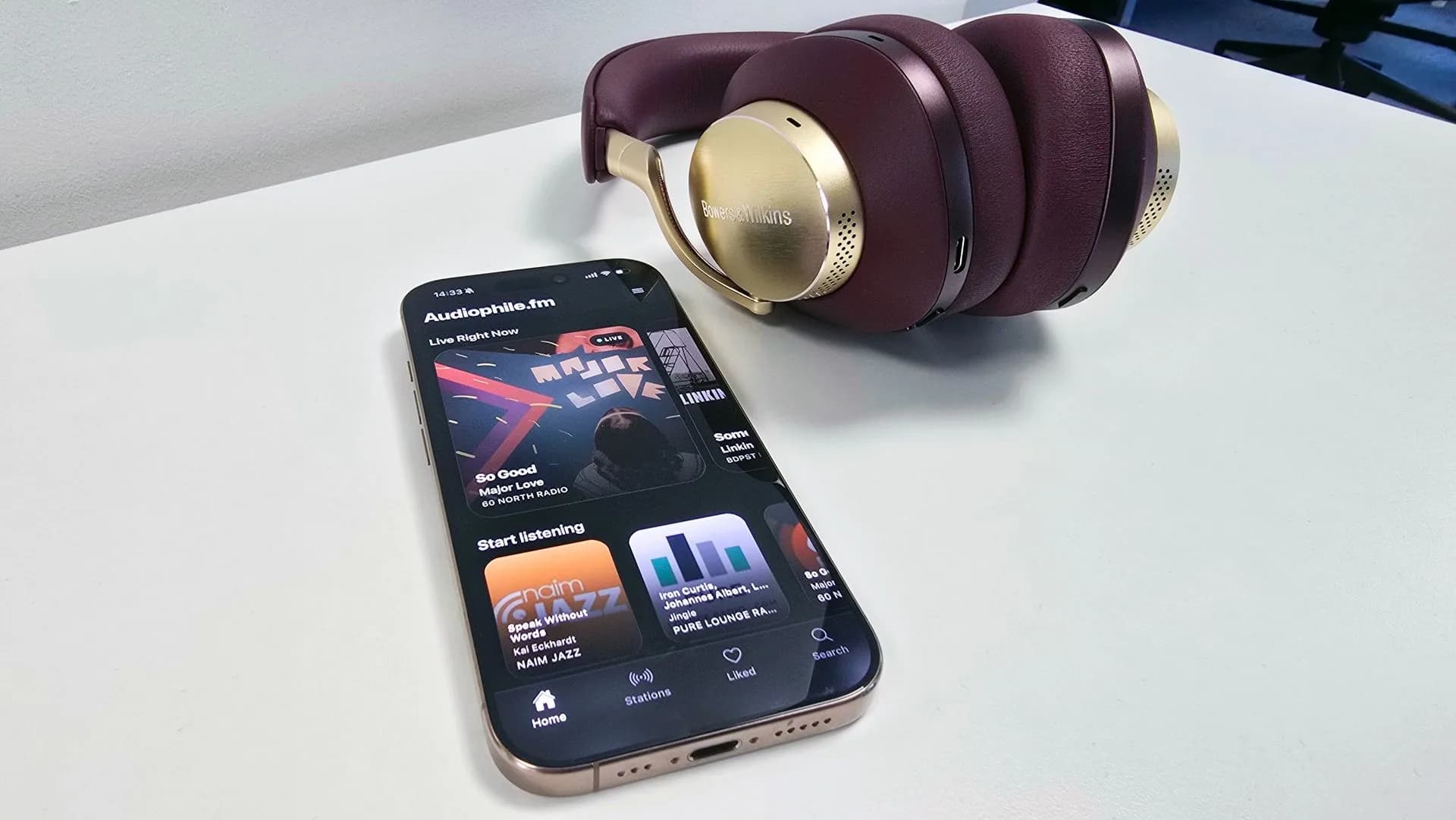 A smartphone displaying an audio playback screen with headphones plugged into a portable DAC.