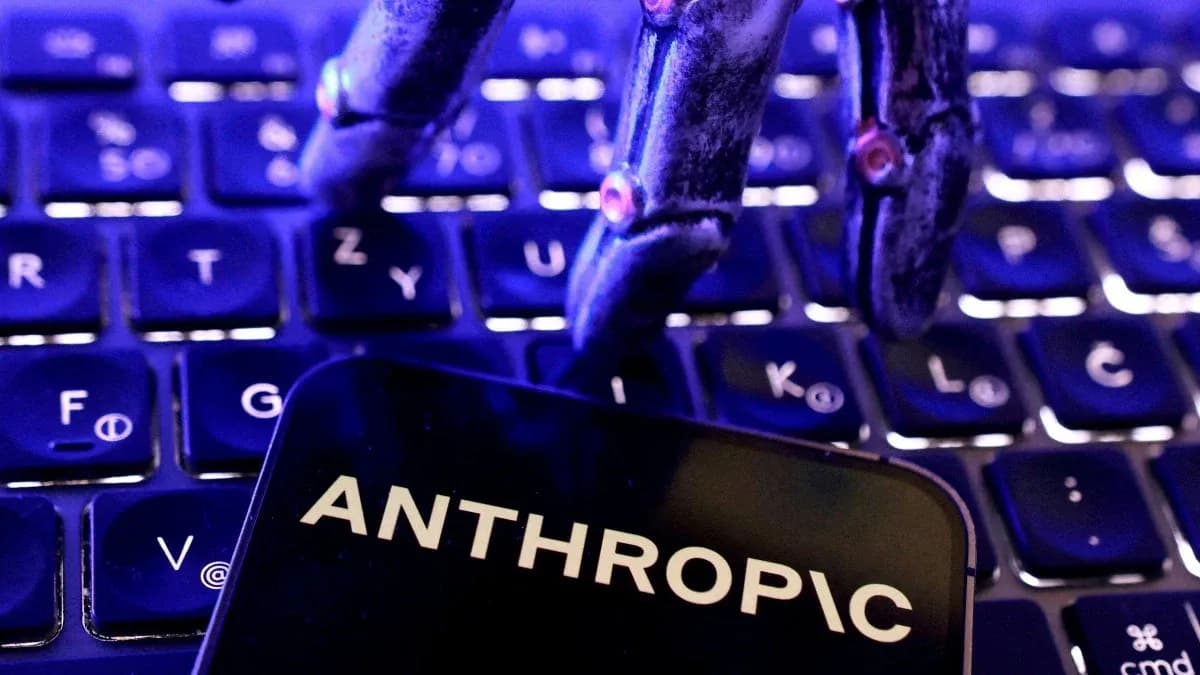 Anthropic Claude logo displayed on a digital screen with code and web interface windows blurred in the background.