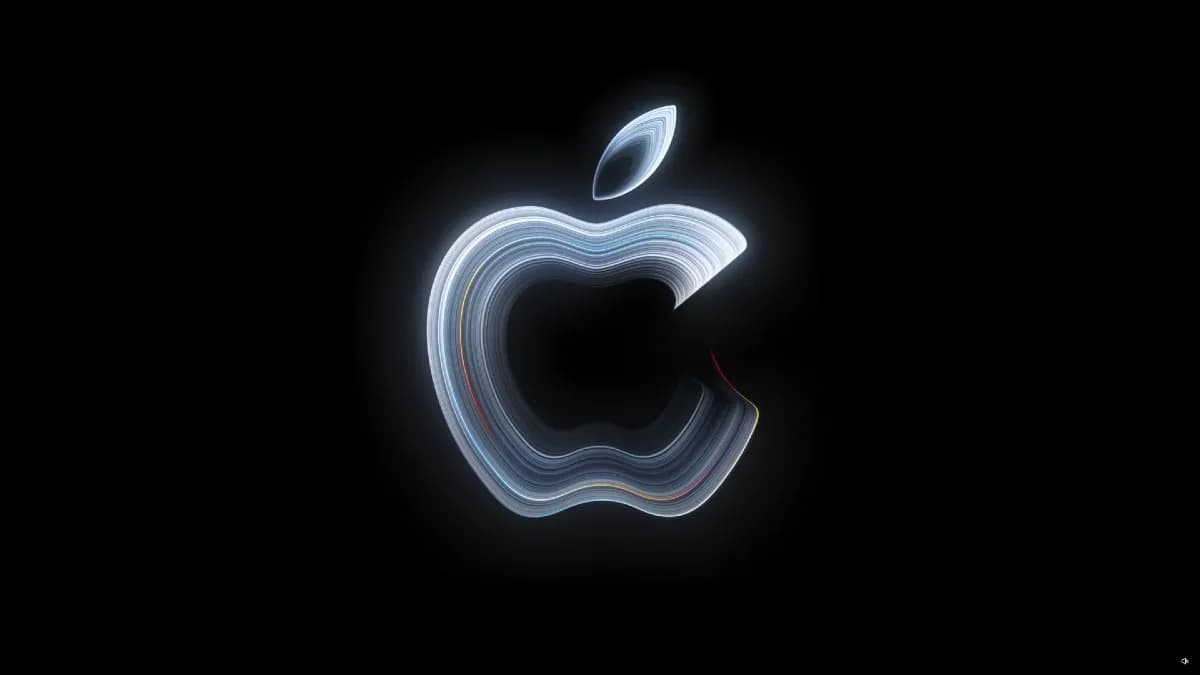 A MacBook Pro laptop shown with a concept OLED touchscreen display next to an Apple event invitation.