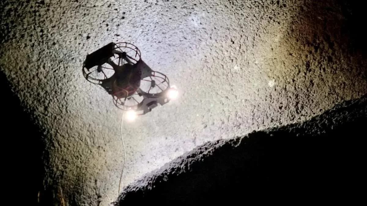 Industrial inspection drone hovering inside a dimly lit steel storage tank.
