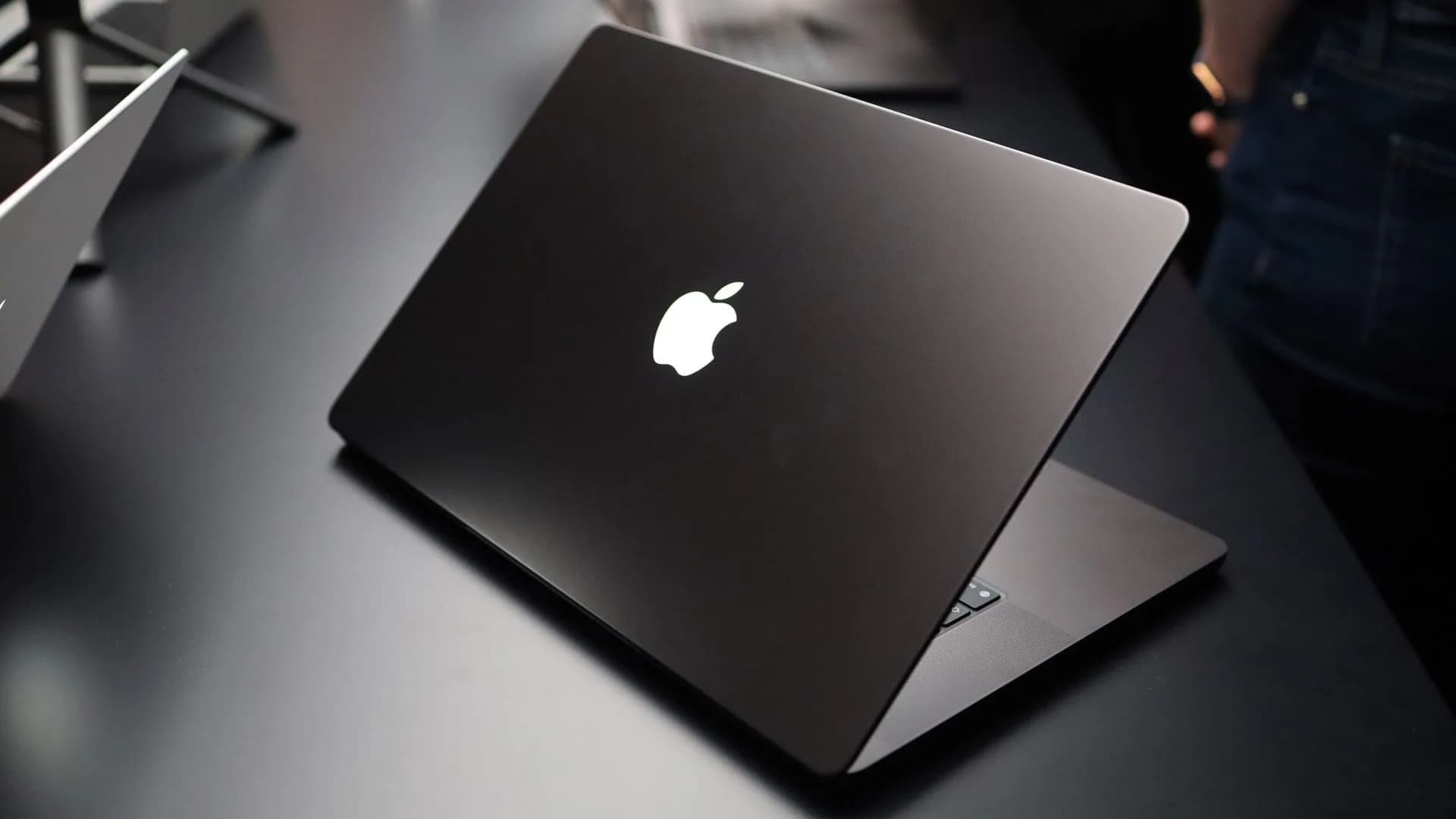 Closed MacBook Pro lid showing the illuminated white Apple logo glowing against the aluminum chassis