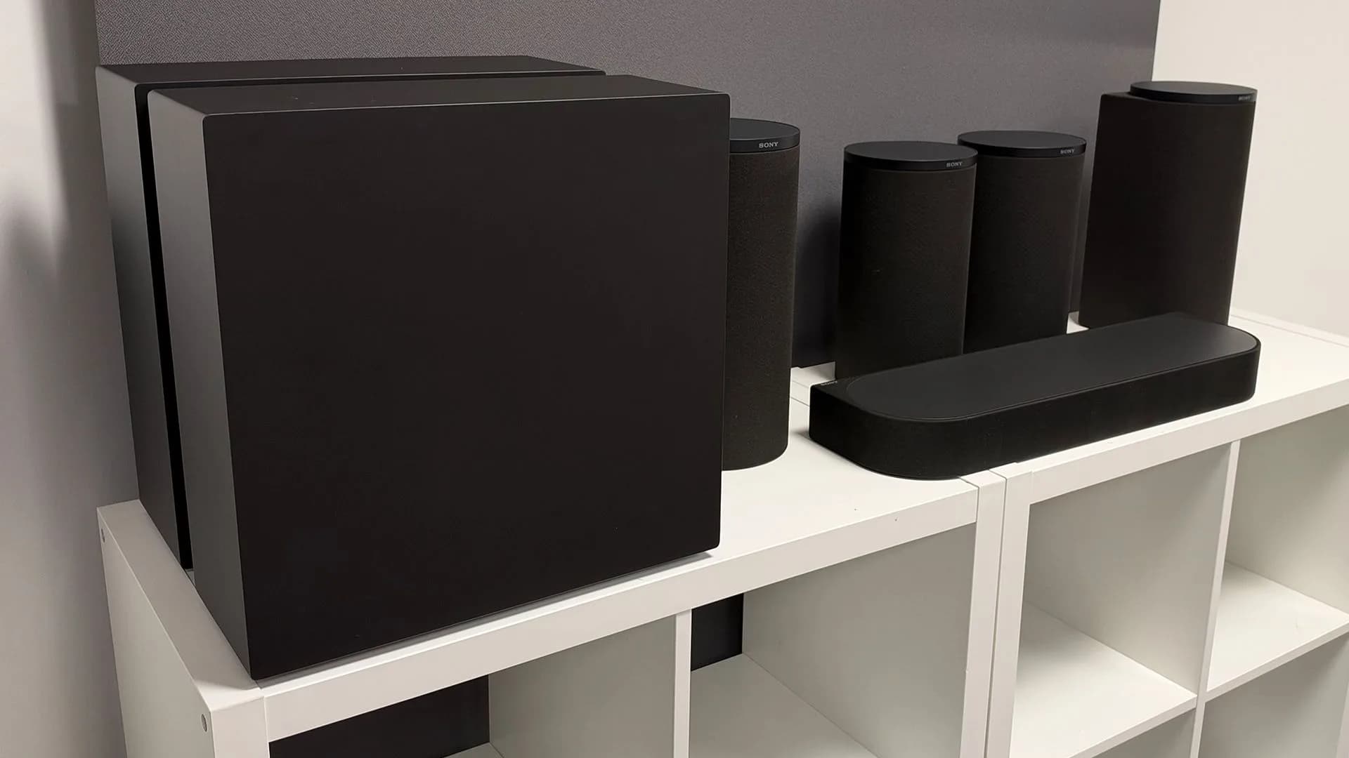 Samsung HW-Q990H soundbar with its wireless subwoofer and surround speakers set up in a living room in front of a television.