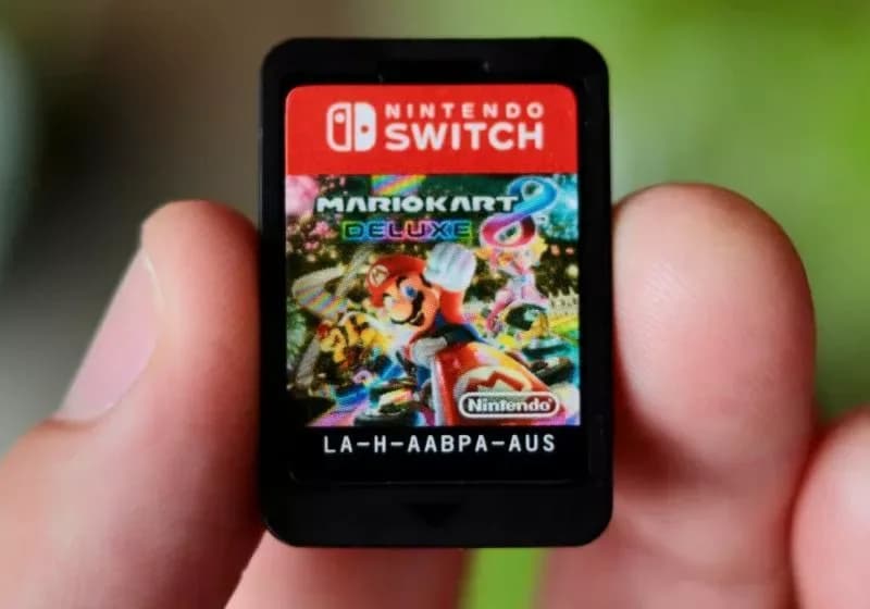 Close up of a Nintendo video game cartridge being held above a game card slot.