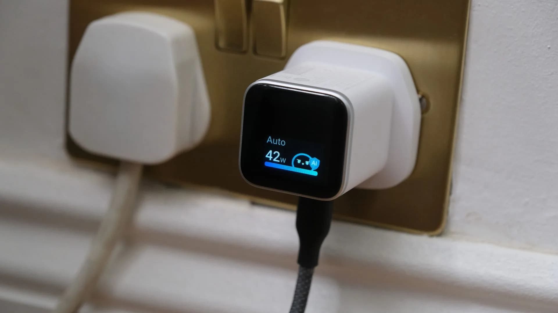 Anker Nano 45W Smart Display charger plugged into a wall outlet showing wattage readout on its miniature color screen