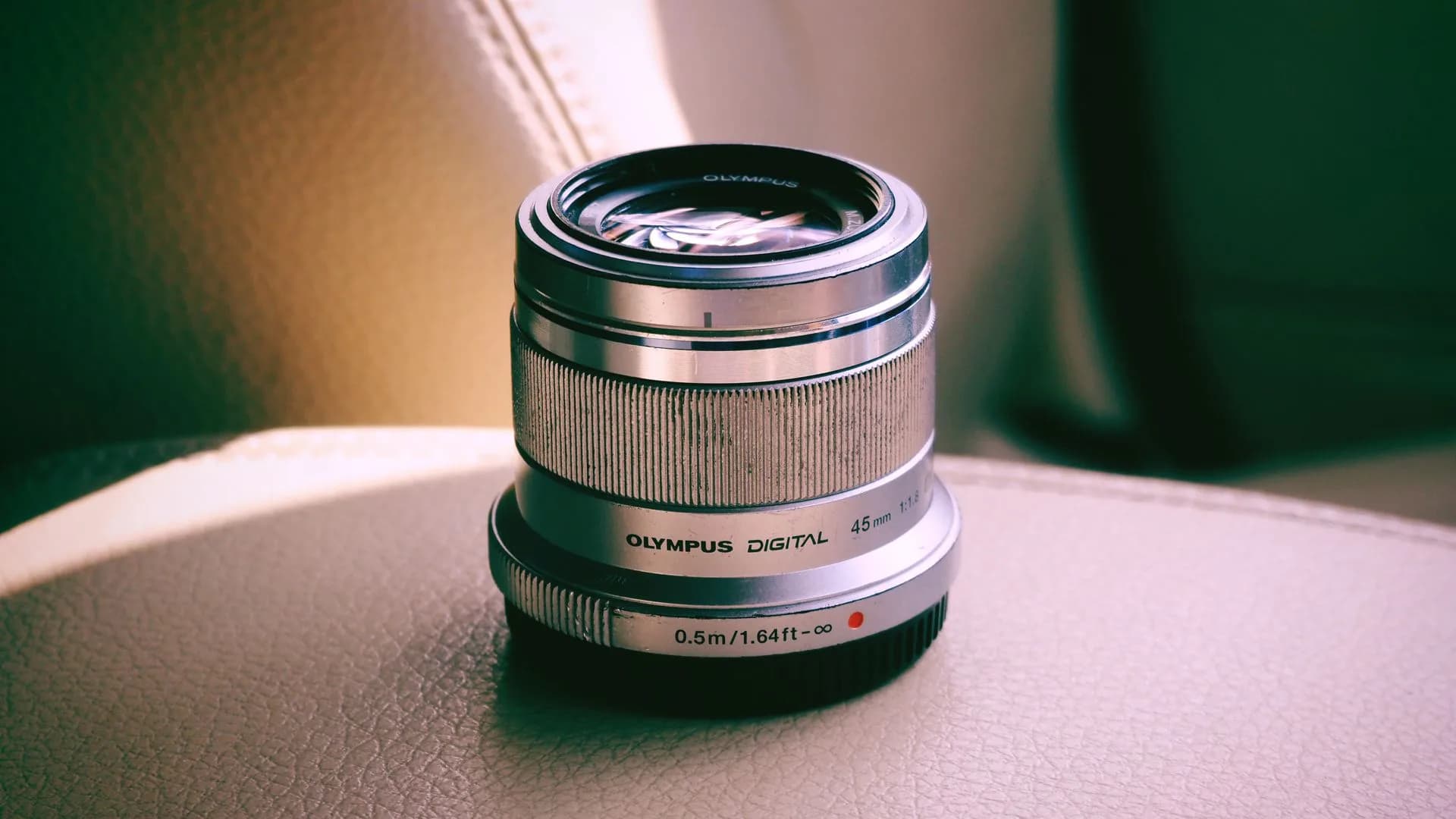 A collection of camera lenses from Pentax, Nikon, Fujifilm and Olympus arranged on a table
