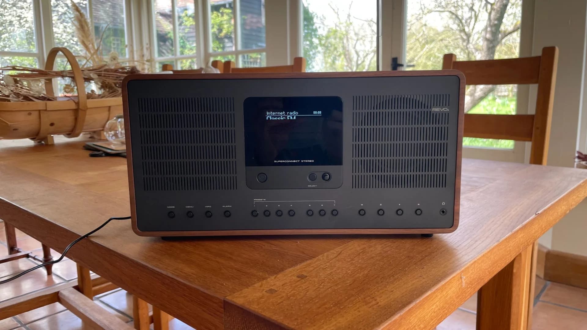 A compact modern DAB radio sitting on a wooden tabletop next to headphones.