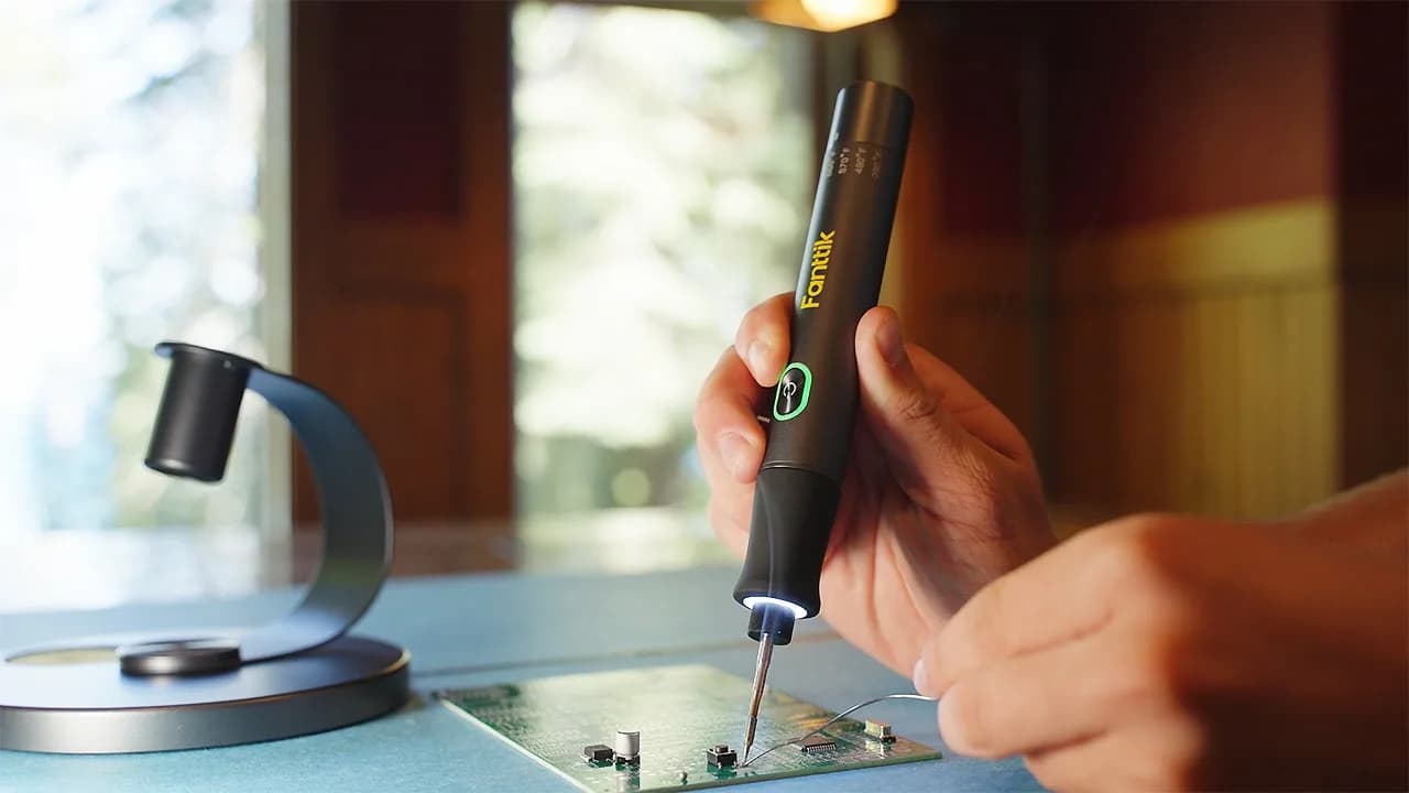 Fanttik T1 Max Cordless Soldering Iron Kit laid out with accessories: tips, desoldering pump, tweezers, and aluminum stand.
