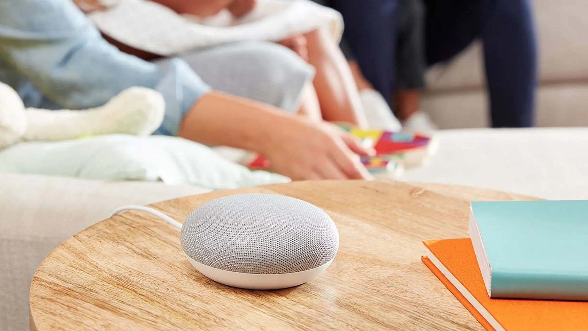 The original Google Home and a Nest Mini smart speaker sitting on a wooden tabletop
