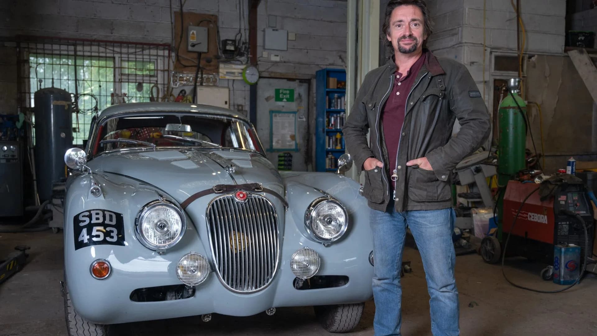 Richard Hammond standing beside a classic car being restored in his workshop