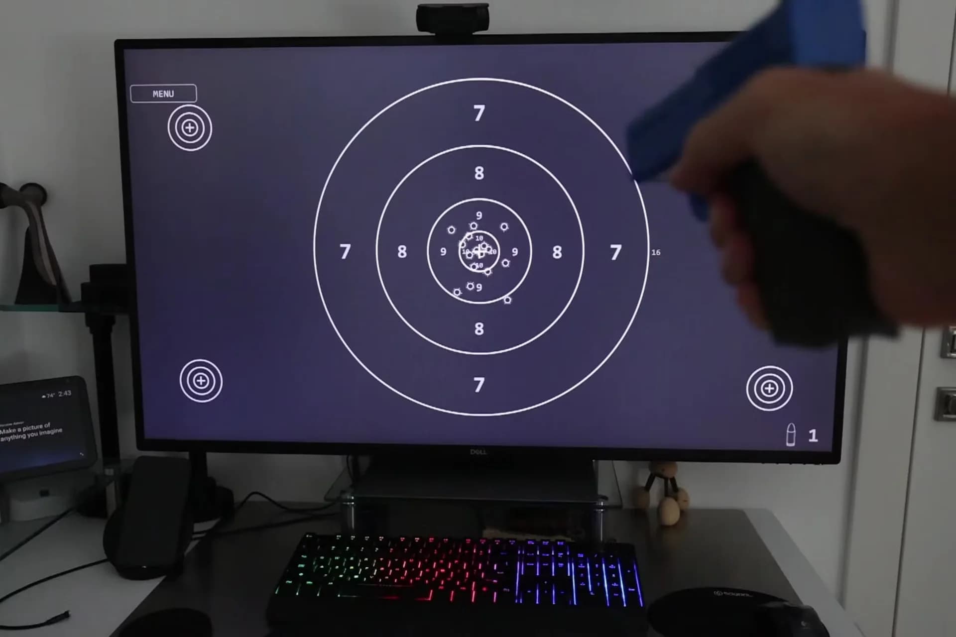 A monitor displaying a shooting range target with a webcam positioned beside it to track laser hits