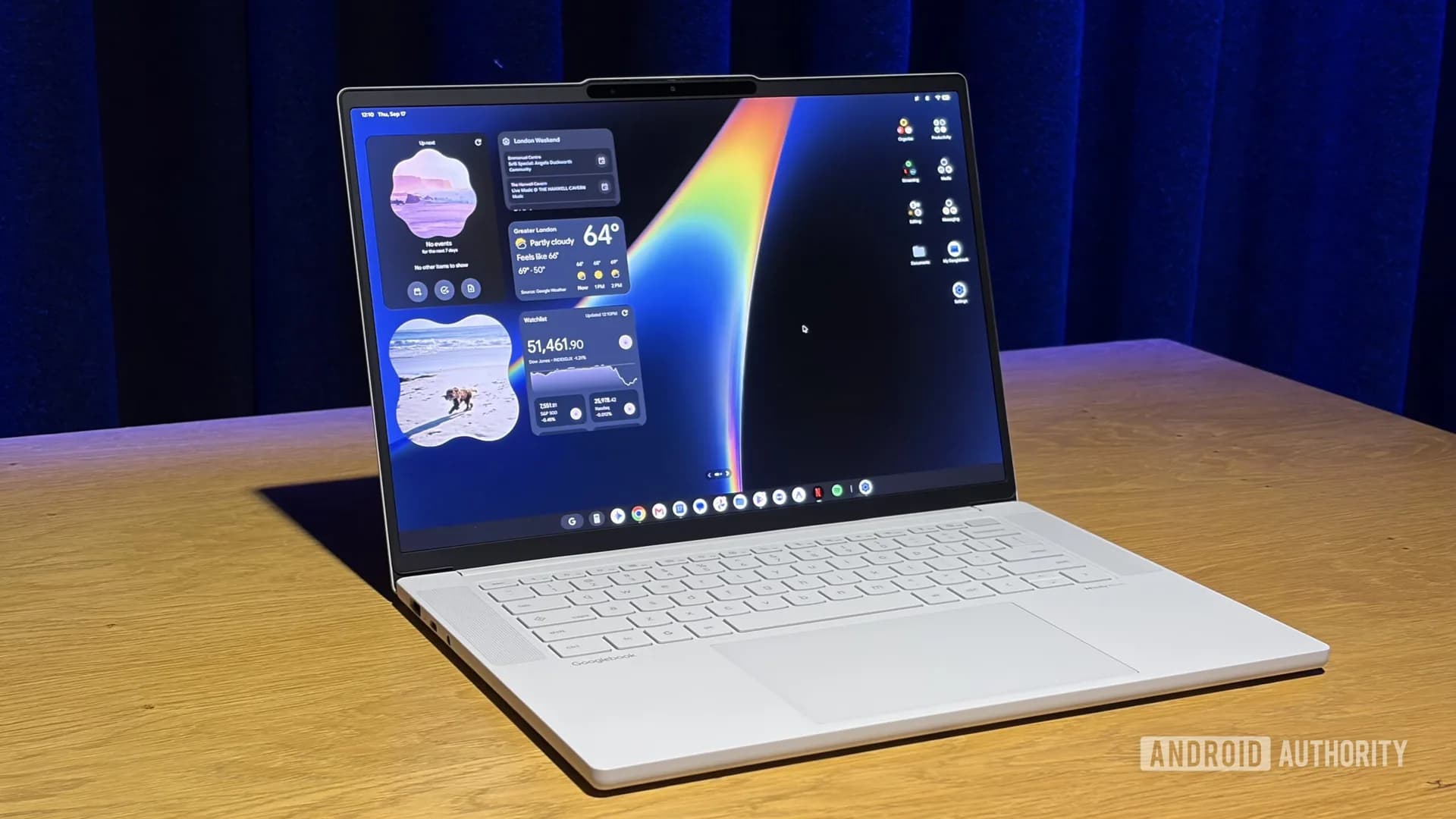 A Googlebook laptop sitting open on an office desk next to an unlocked Android smartphone