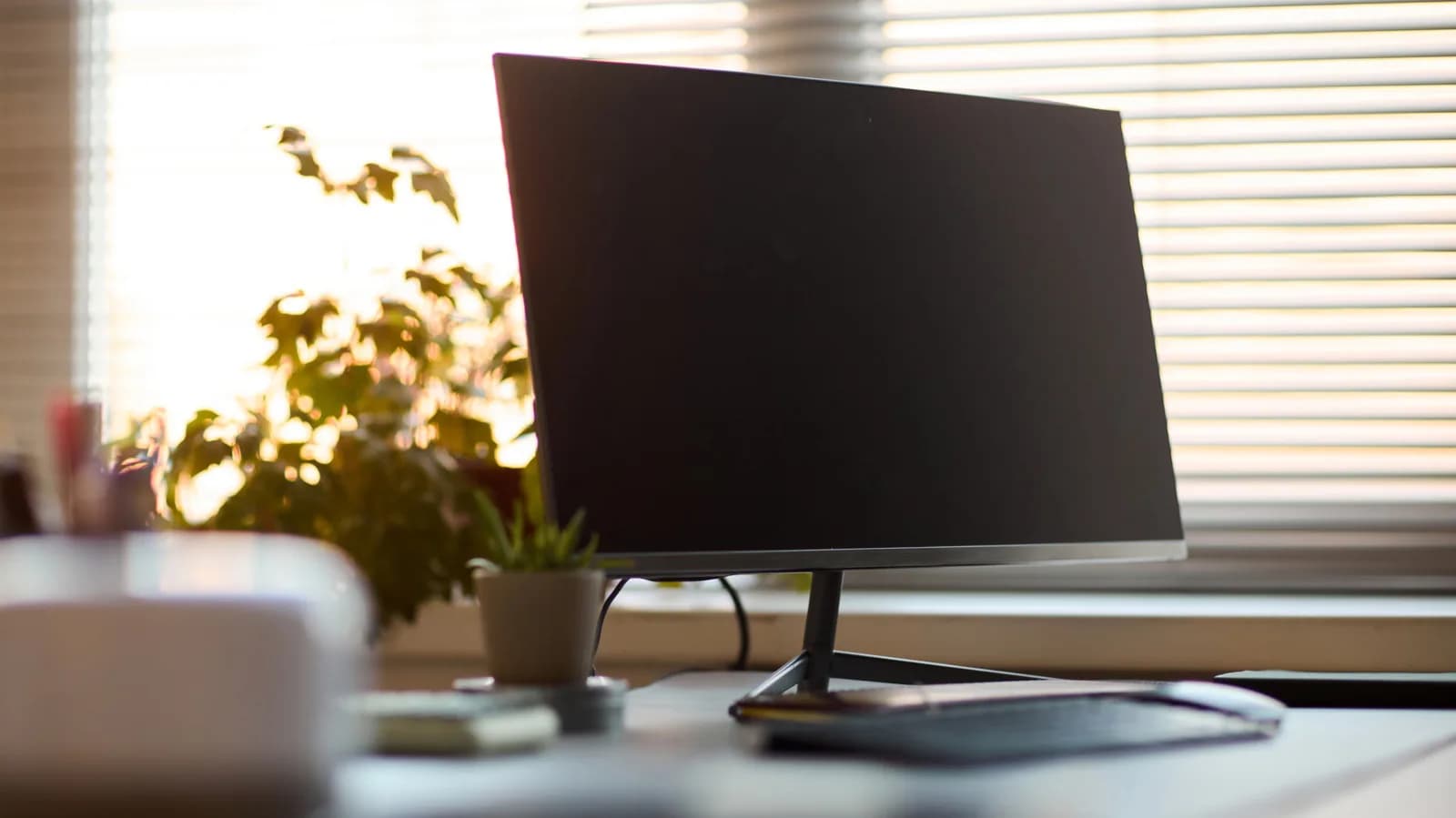 ASUS NUC 15 Pro mini PC mounted behind a monitor, connected via single Thunderbolt cable to keyboard, mouse and dual displays