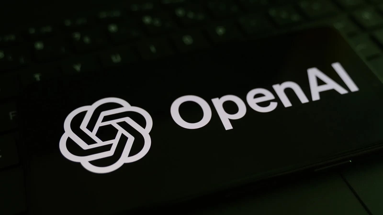 OpenAI logo displayed on a screen alongside abstract network and server imagery