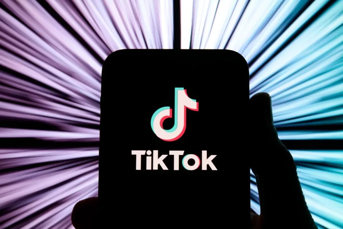 TikTok logo overlaid on a smartphone screen showing a video with a 'Buy Now' button and chat bubble icon