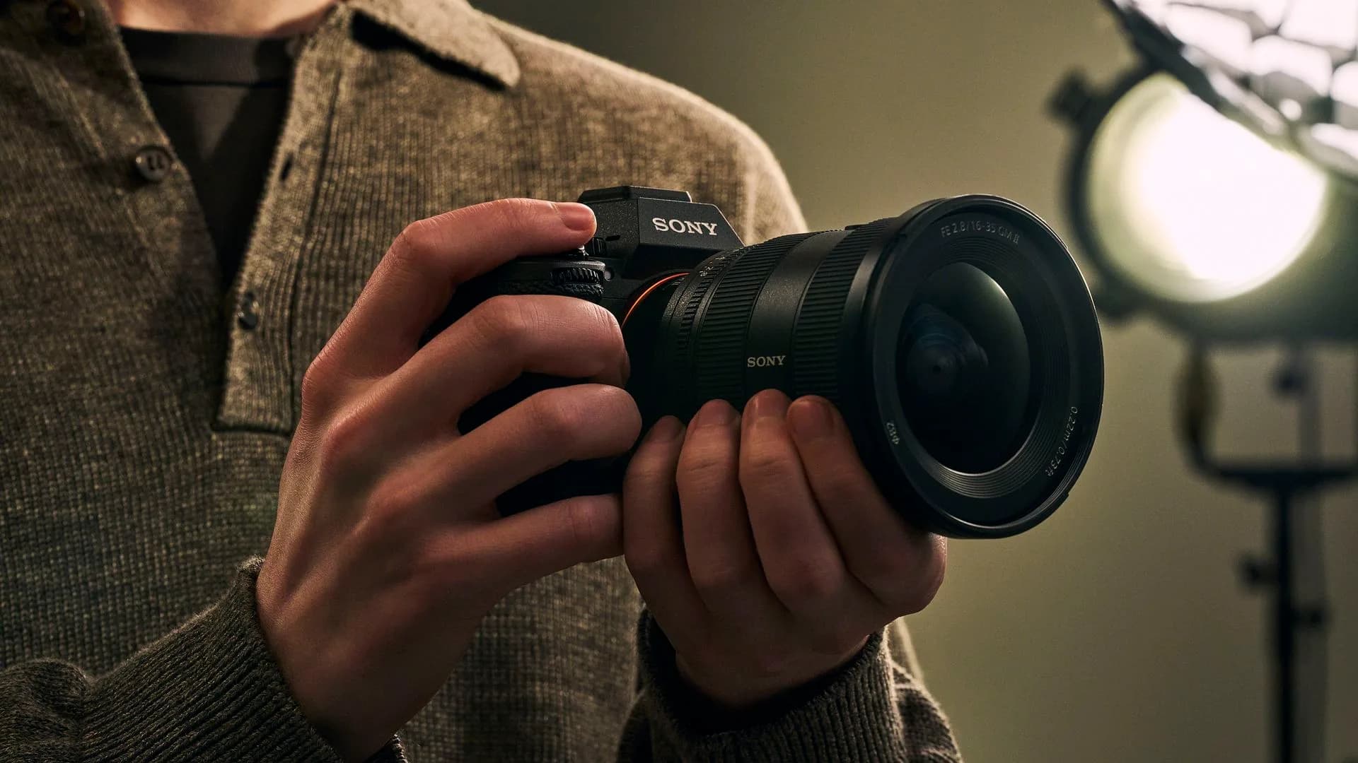 A Sony Alpha mirrorless camera body shown alongside a Cyber-shot compact camera on a dark background
