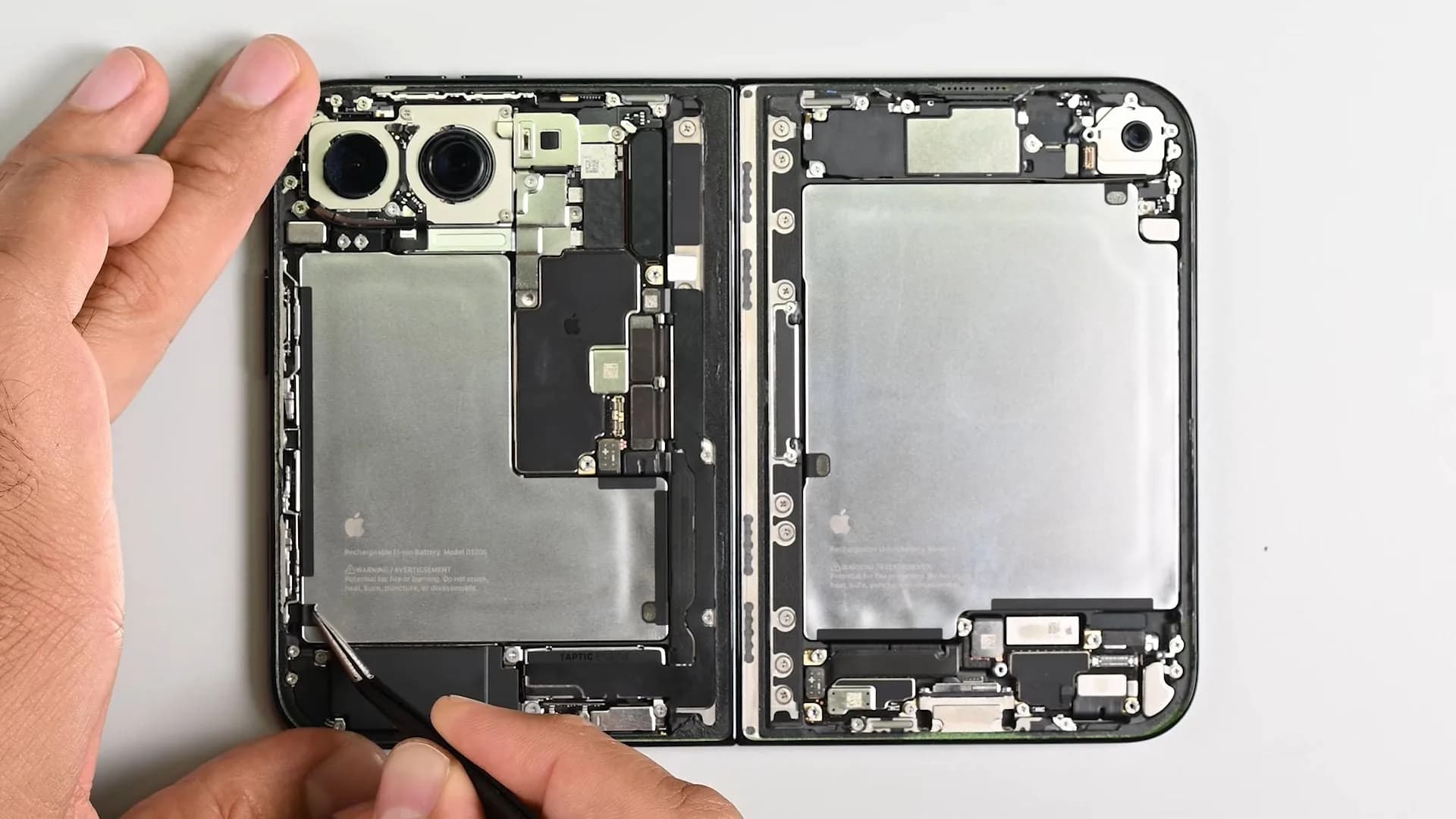 iPhone Duo disassembled on a workbench during an iFixit teardown, showing its internal hinge and battery components