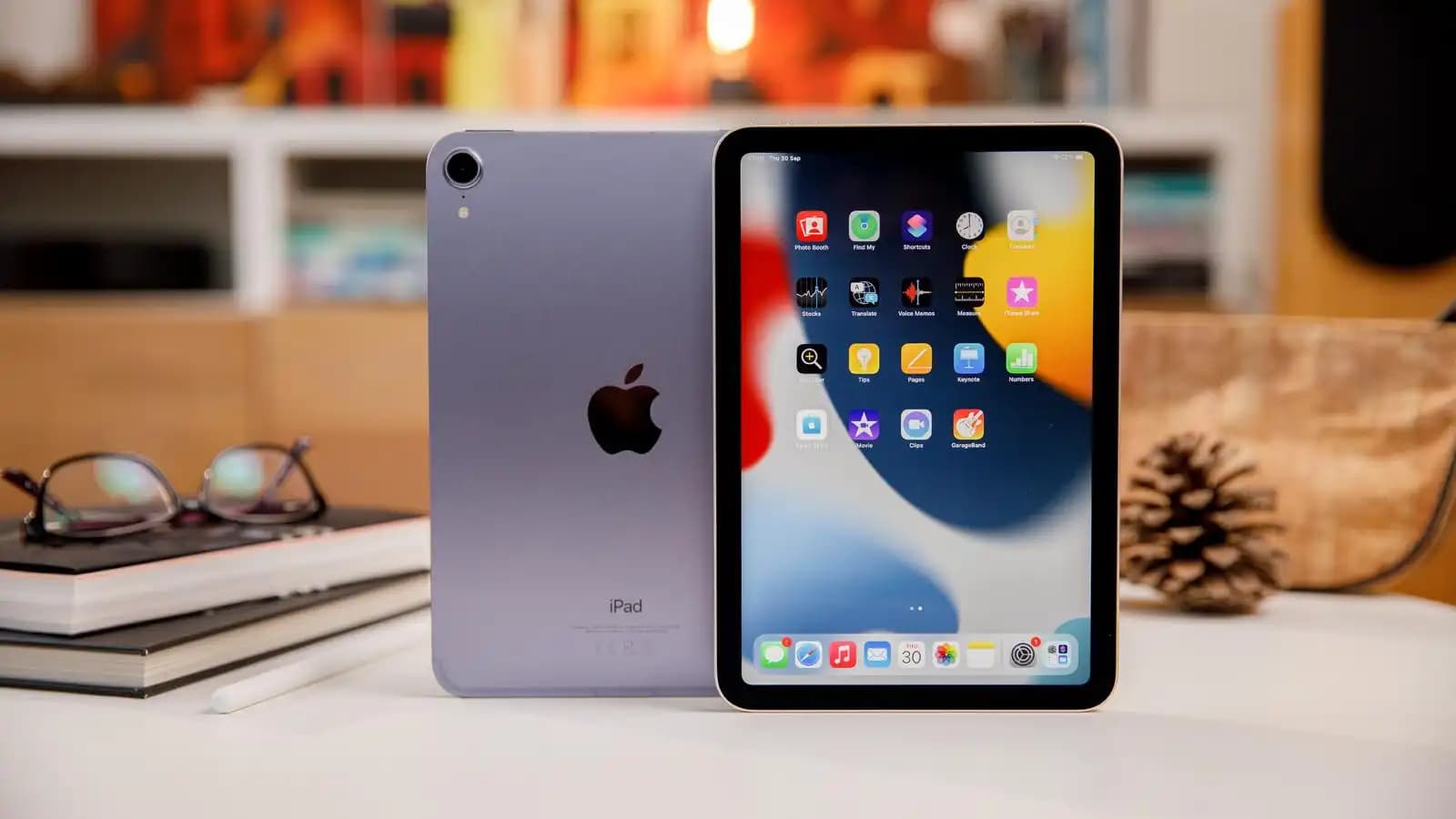 An Apple iPad mini resting on a clean wooden desk beside a digital stylus.