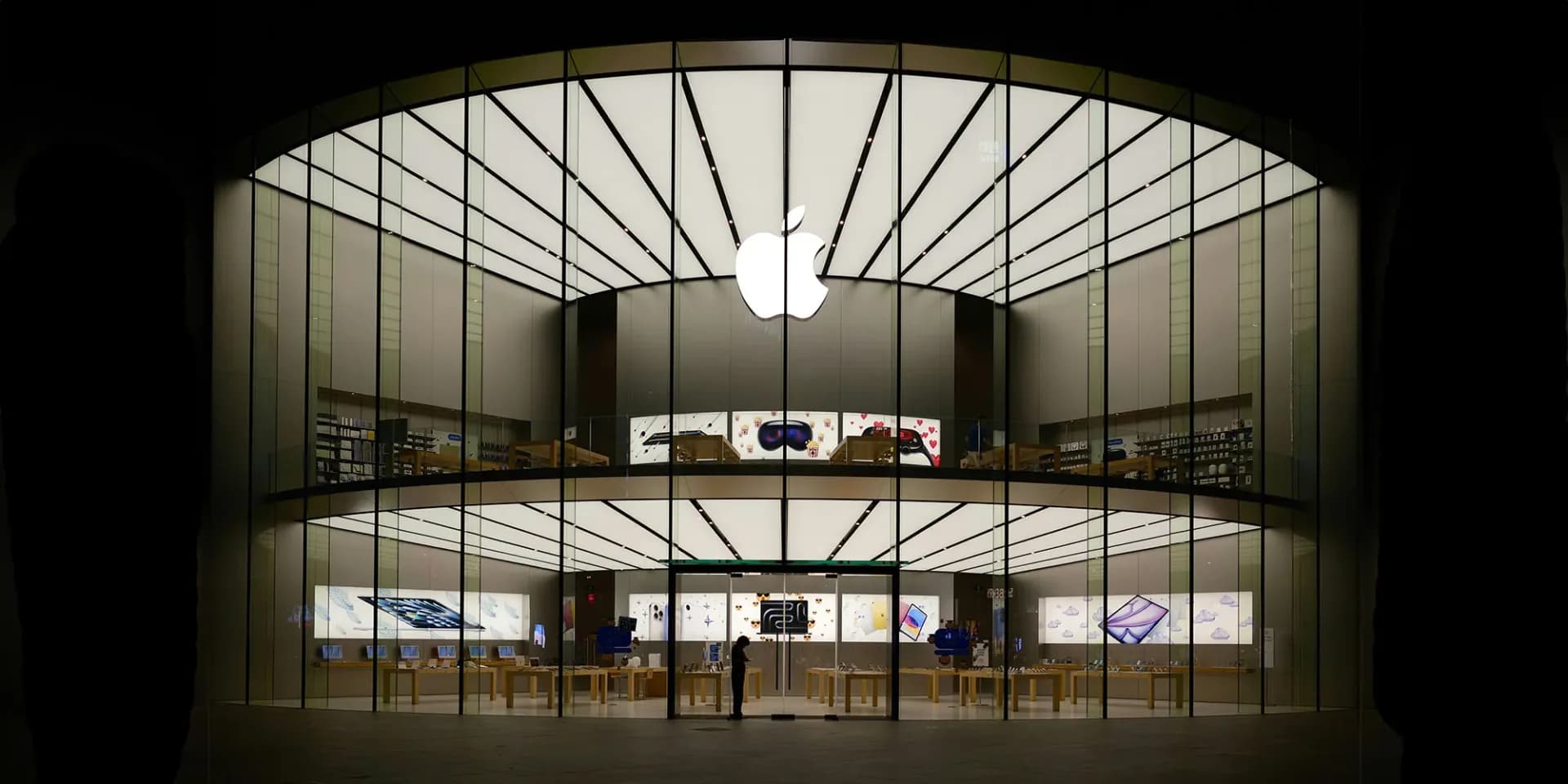 Close up of an Apple logo displayed on the back of a modern smartphone against a dark background