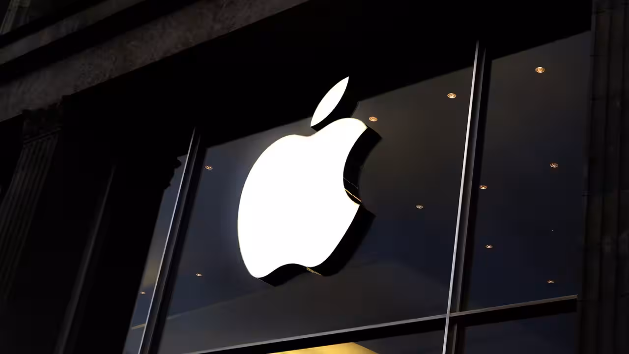 Apple logo on a glass storefront with reflections of a busy street