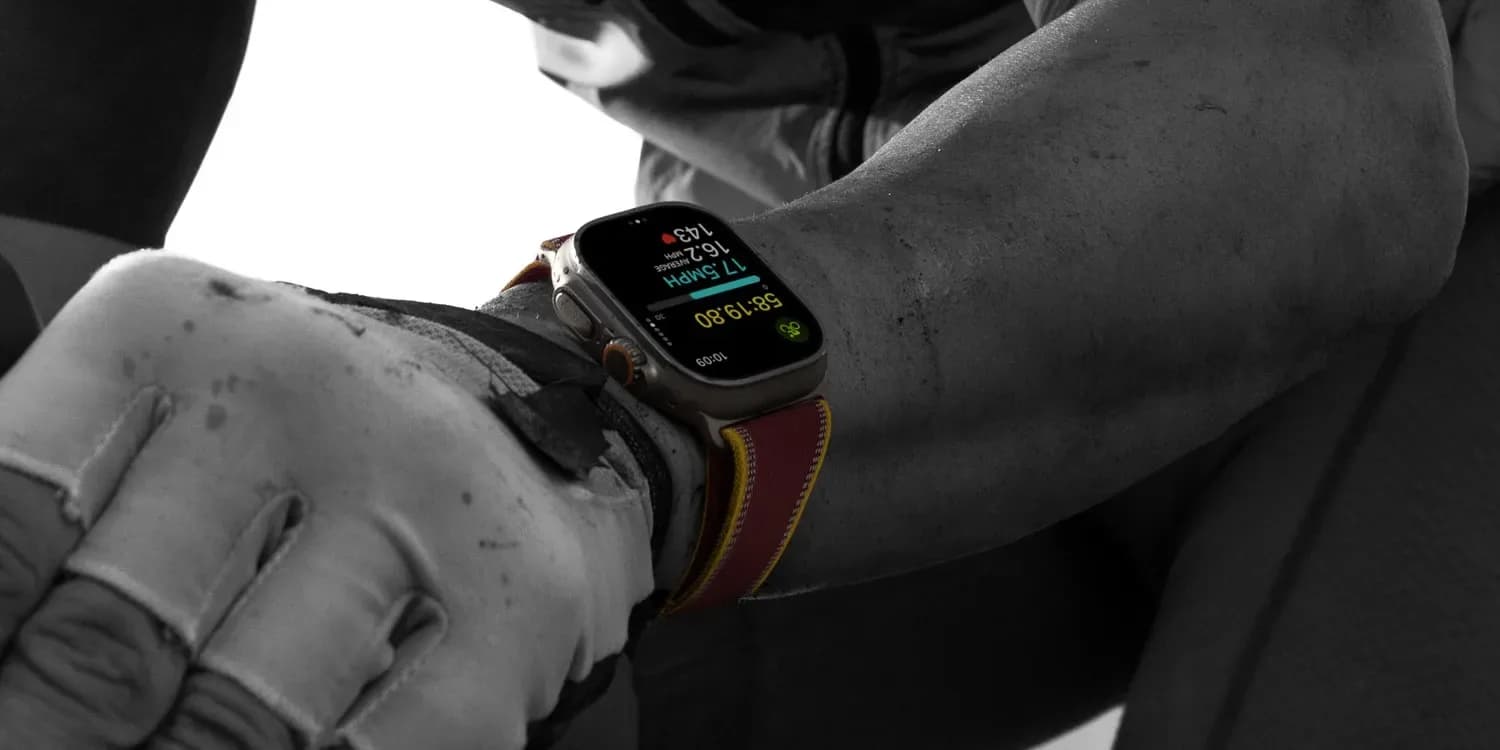 Apple Watch Ultra 4 in black titanium with burgundy Trail Loop band, displayed on a dark surface
